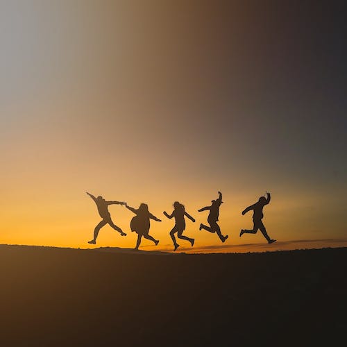 Silhouettes of a group of people running at sunset.